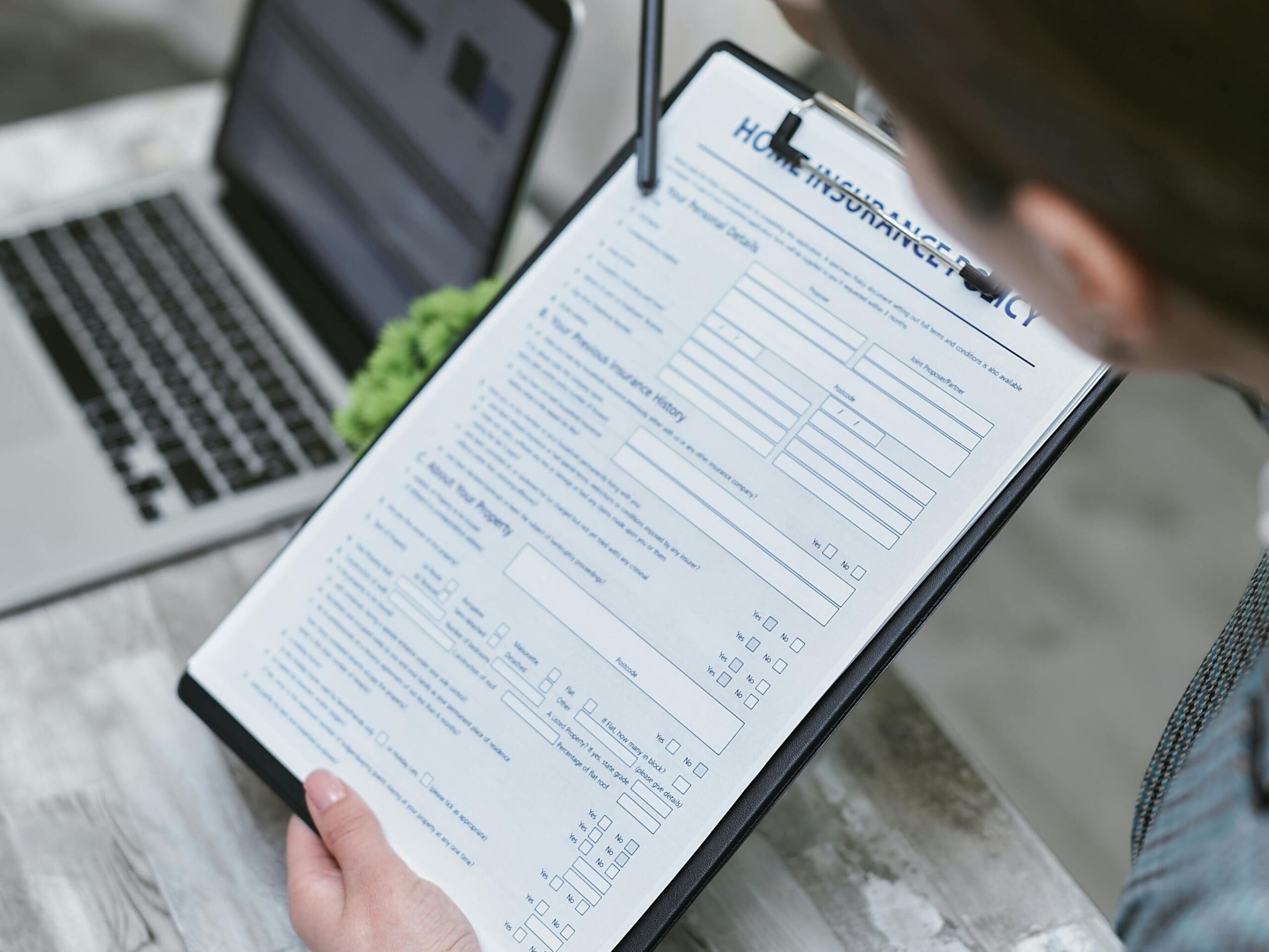 Passport , Visa Agency & Other Documentation (Non-Government) An adult reviews a home insurance policy document at a desk with a pen and laptop.